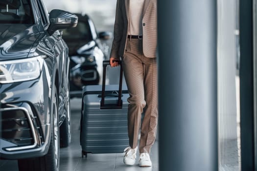 Tourist with lugagge. Woman is indoors near brand new automobile indoors.