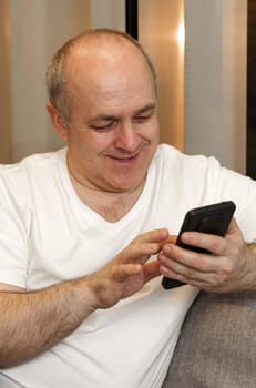A man sits on the couch and browses social networks and videos. Close-up. Vertical frame.