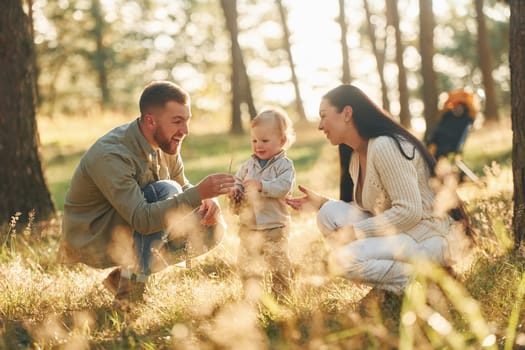 Having fun. Happy family of father, mother and little daughter is in the forest.