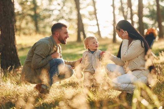 Having fun. Happy family of father, mother and little daughter is in the forest.