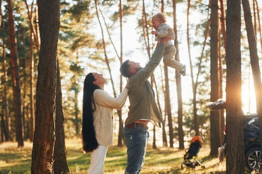 Summertime happiness. Family of father, mother and little daughter is in the forest.