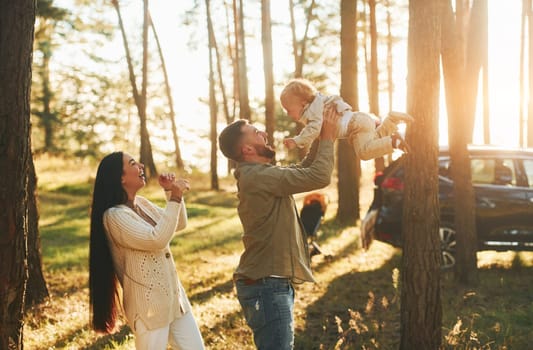 Summertime happiness. Family of father, mother and little daughter is in the forest.