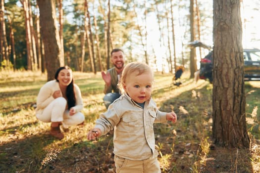 Summertime happiness. Family of father, mother and little daughter is in the forest.