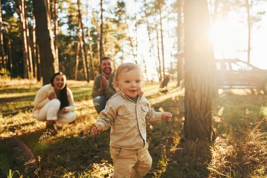 Summertime happiness. Family of father, mother and little daughter is in the forest.