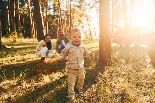 Young people. Happy family of father, mother and little daughter is in the forest.