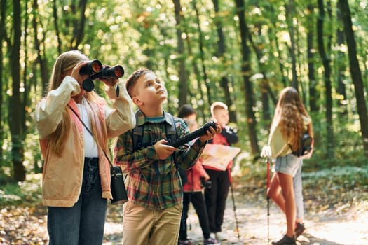 New places. Kids in green forest at summer daytime together.