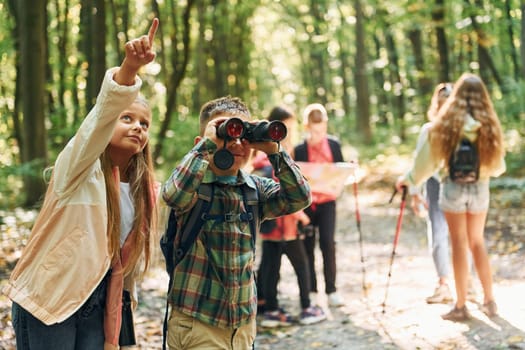 New places. Kids in green forest at summer daytime together.