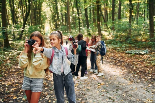 Looking for a path. Kids in green forest at summer daytime together.