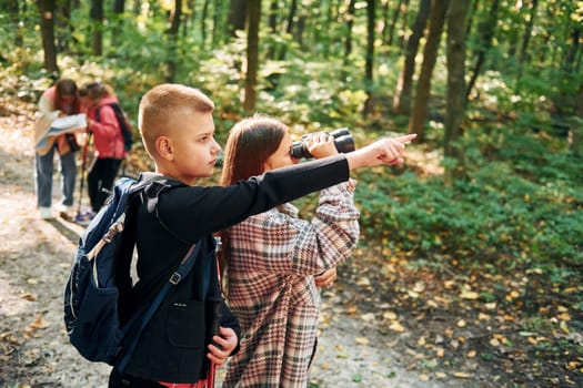 Conception of hiking. Kids in green forest at summer daytime together.