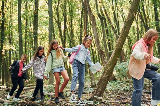 Walking on the log. Kids in green forest at summer daytime together.