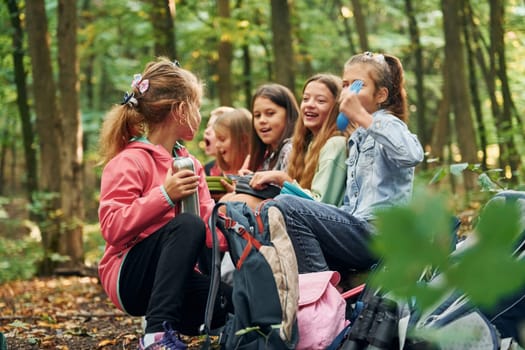 Sitting and having a rest. Kids in green forest at summer daytime together.