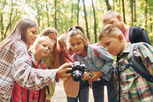 Front view. Kids in green forest at summer daytime together.