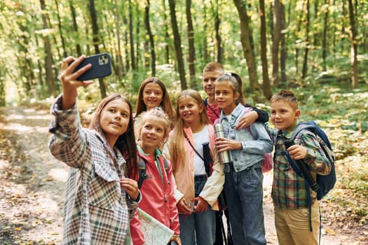 Front view. Kids in green forest at summer daytime together.
