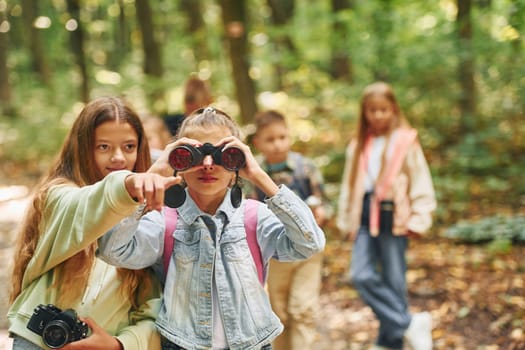 Front view of kids that is in green forest at summer daytime together.