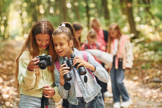 Front view of kids that is in green forest at summer daytime together.