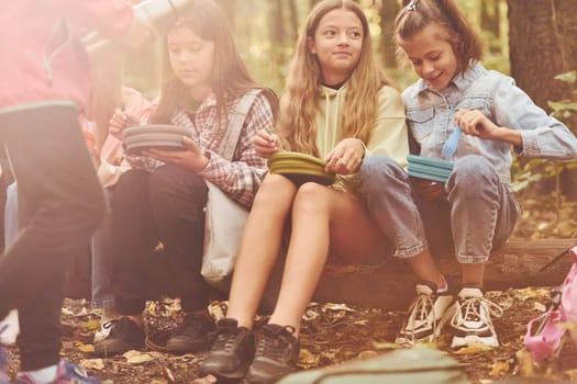 Sitting and having a rest. Kids in green forest at summer daytime together.