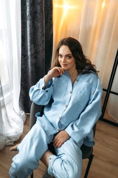 Portrait of a beautiful woman in a light blue suit, who is sitting in a chair. Vertical frame.