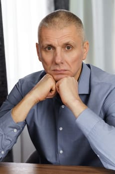 A portrait of a serious man holding his hand on his face and looking into the cell. Close-up.