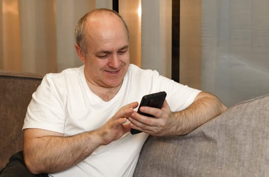 A man sits on the couch and browses social networks and videos. Close-up.