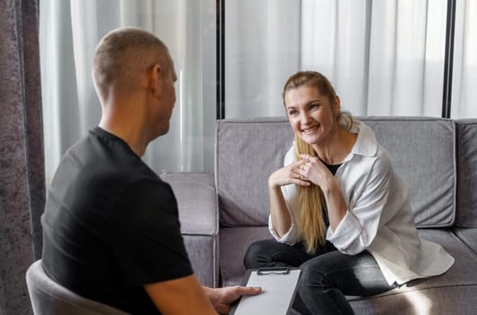 A man psychologist carefully listens to the patient - a woman who emotionally talks about himself, makes notes.