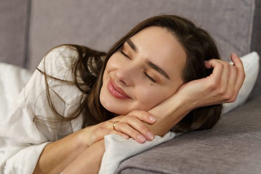 A young beautiful woman lies on the sofa, rests, smiles in her sleep.