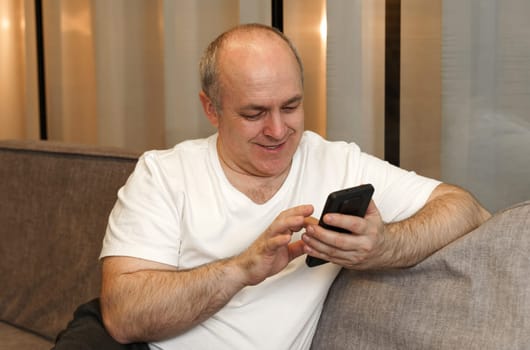 A man sits on the couch and browses social networks and videos. Close-up.