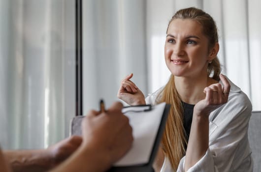 At the reception of a male psychologist, a woman who talks about herself makes notes.