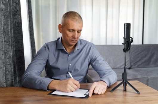 Businessman, psychologist communicates with the Internet audience using a smartphone. Video blogger broadcasts via smartphone.