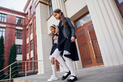 Conception of education. Two schoolgirls is outside together near school building.