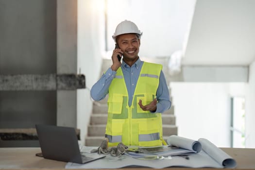 Young asian male engineer construction talking on phone at construction site.