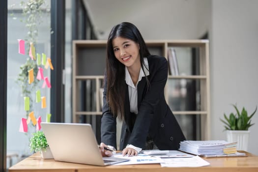 Young happy business woman worker at desk working on laptop in corporate office.