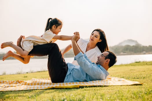 Family fun. Happy family father holding small kid daughter on straight legs with mother in the park, child girl smiling flying in air play airplane, little girl open arms and flying like plane