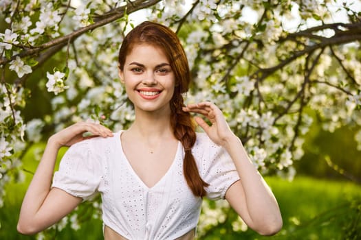 joyful woman posing standing next to a flowering tree enjoying nature. High quality photo