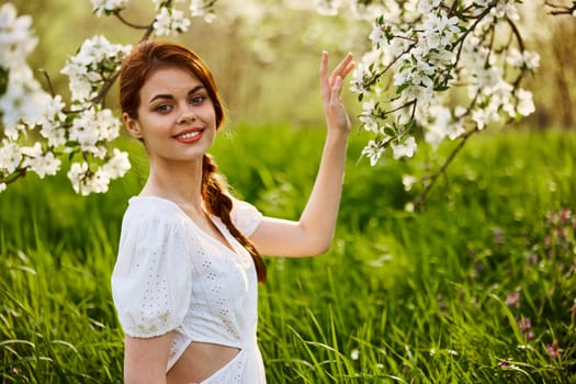 Portrait of a beautiful woman looking at the camera touching the flowers of an apple tree. High quality photo