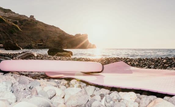 Young woman with long hair in white swimsuit and boho style braclets practicing outdoors on yoga mat by the sea on a sunset. Women's yoga fitness routine. Healthy lifestyle, harmony and meditation