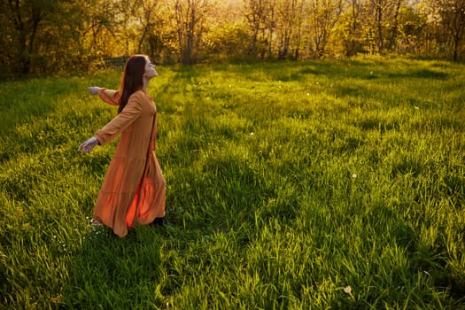 a joyful woman runs through a green field with her hands behind her back, enjoying a warm summer day and nature during the sunset. Horizontal photography in nature. High quality photo