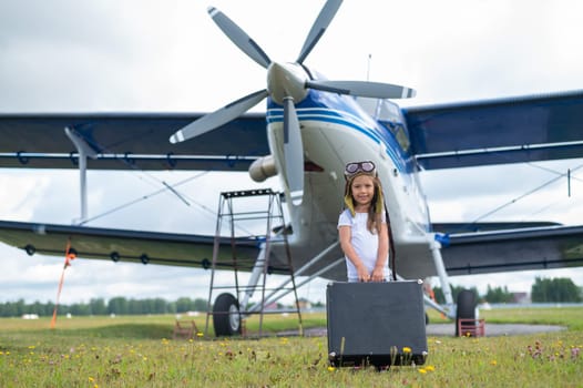 A cute little girl playing on the field by private jet dreaming of becoming a pilot.