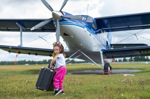 A cute little girl playing on the field by a four-seater private jet dreaming of becoming a pilot.