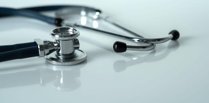 Stethoscope on a white reflective surface. Health care and surgical concept. Close-up.