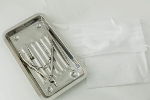 Medical instrument for pedicure, mask and surgical cap on a white background.