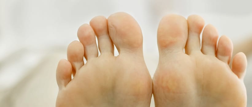Two feet of a woman pressed against each other. Toes close-up, foot partially visible. Close-up
