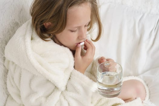 A girl takes a thermometer from the table where the medicines are. Medical concept.