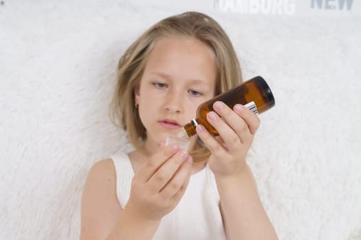 Sick teenager girl pours medicine from a jar. Medical concept.