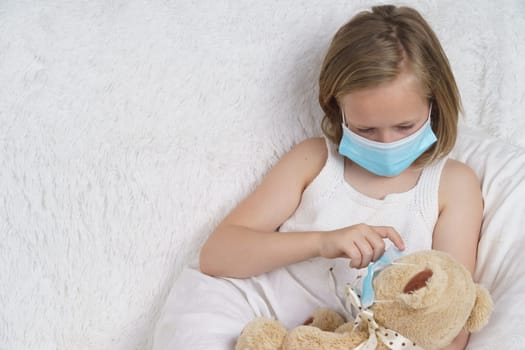 Sick teenage girl puts on a medical protective mask for a toy. Medical concept.