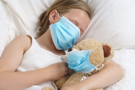 A sick teenage girl is playing with a toy wearing a protective mask. Medical concept.