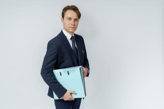 A businessman in a blue suit holds folders on a white background. Business and finance concept