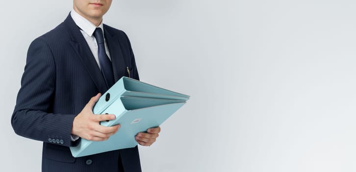 Businessman in a blue suit holds a folder in his hands on a white background. No face visible.