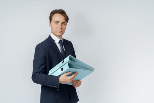 A businessman in a blue suit holds folders on a white background. Business and finance concept