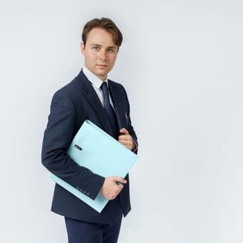 A businessman in a blue suit holds folders on a white background. Business and finance concept