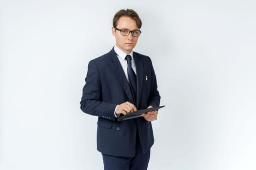 Portrait of a businessman in a blue suit holding an electronic tablet on a white background. Business and finance concept